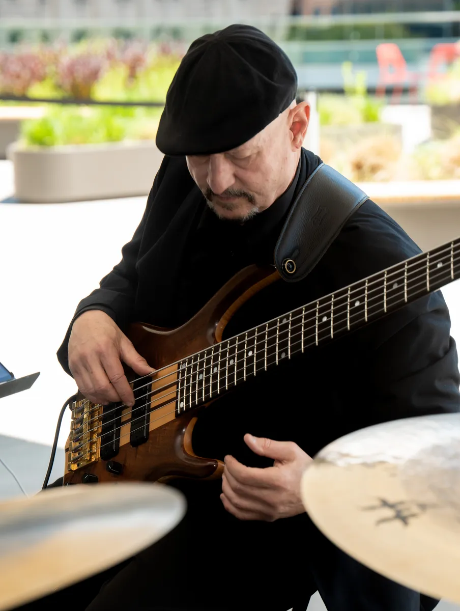 Russ Rodgers in a beret playing his bass in warm daylight