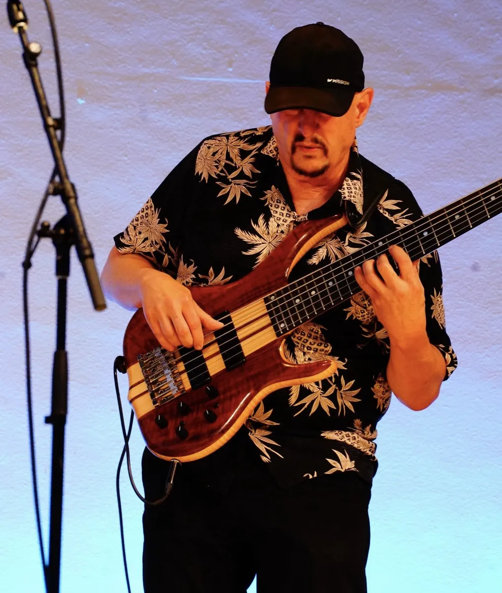Russ Rodgers playing bass on a blue-lit stage