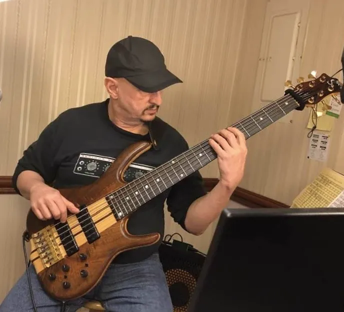 Russ playing bass at his teaching setup, computer monitor in frame