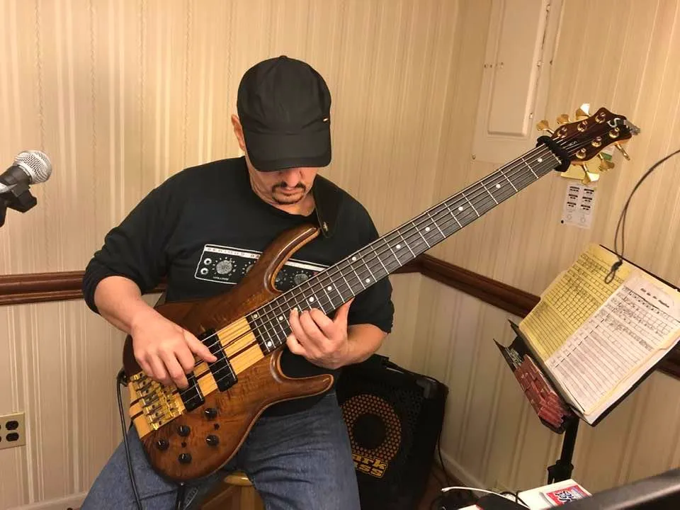 Russ playing bass with sheet music and a bass amp visible behind him
