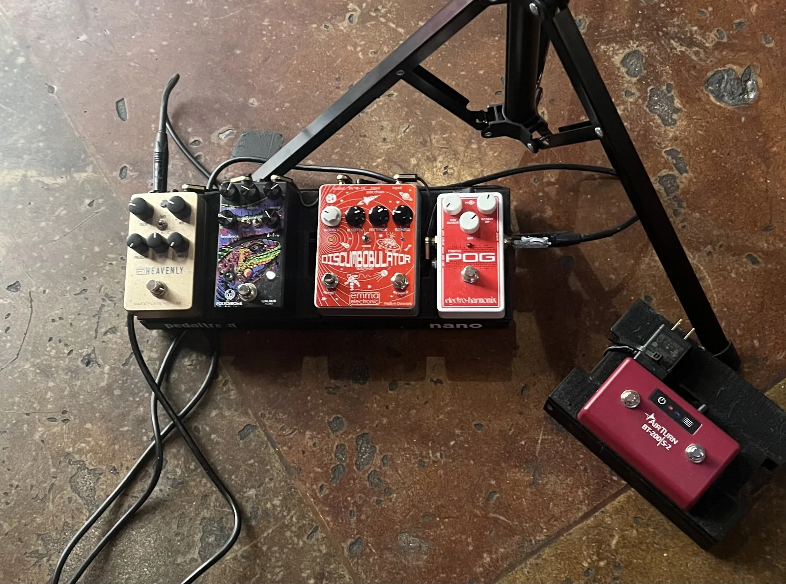 The Pedaltrain Nano effects board on a stone floor at a gig, with the AirTurn page turner beside it