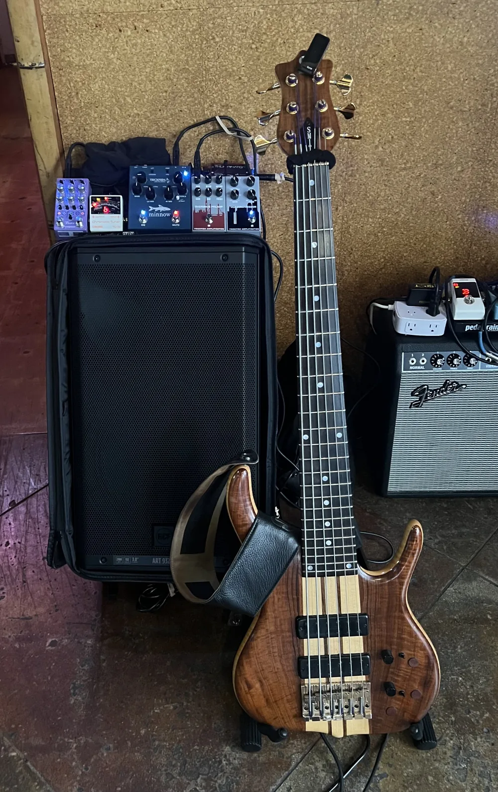Russ's six-string Ken Smith beside an RCF ART 932-A in its cover, with the Trickfish pedals set on top, against a cork wall