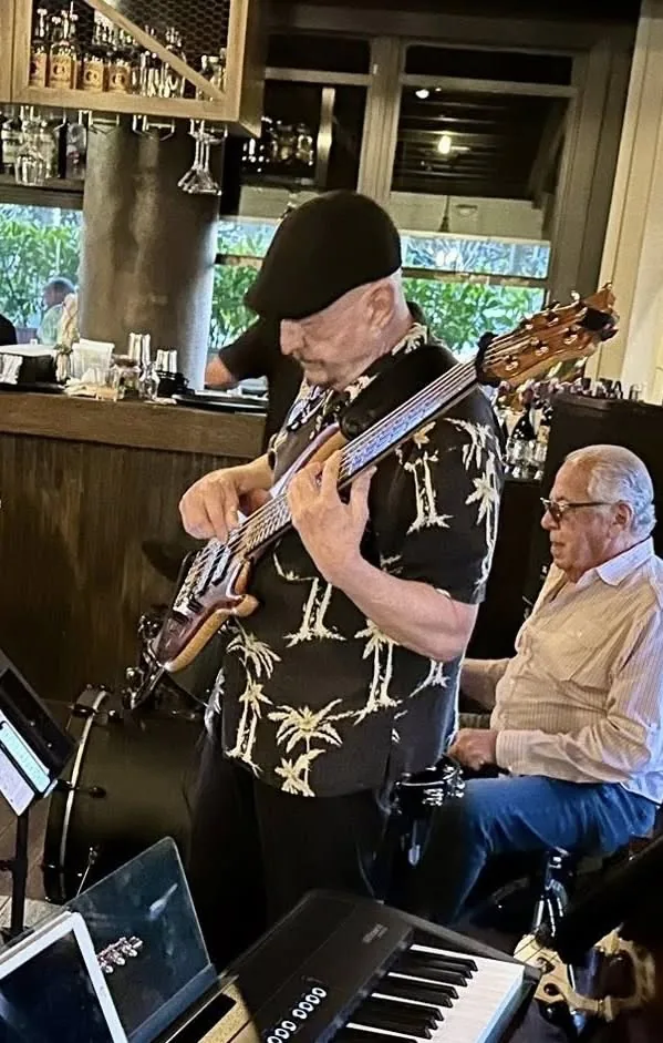 Russ Rodgers standing with his six-string bass at a restaurant jazz gig with a pianist